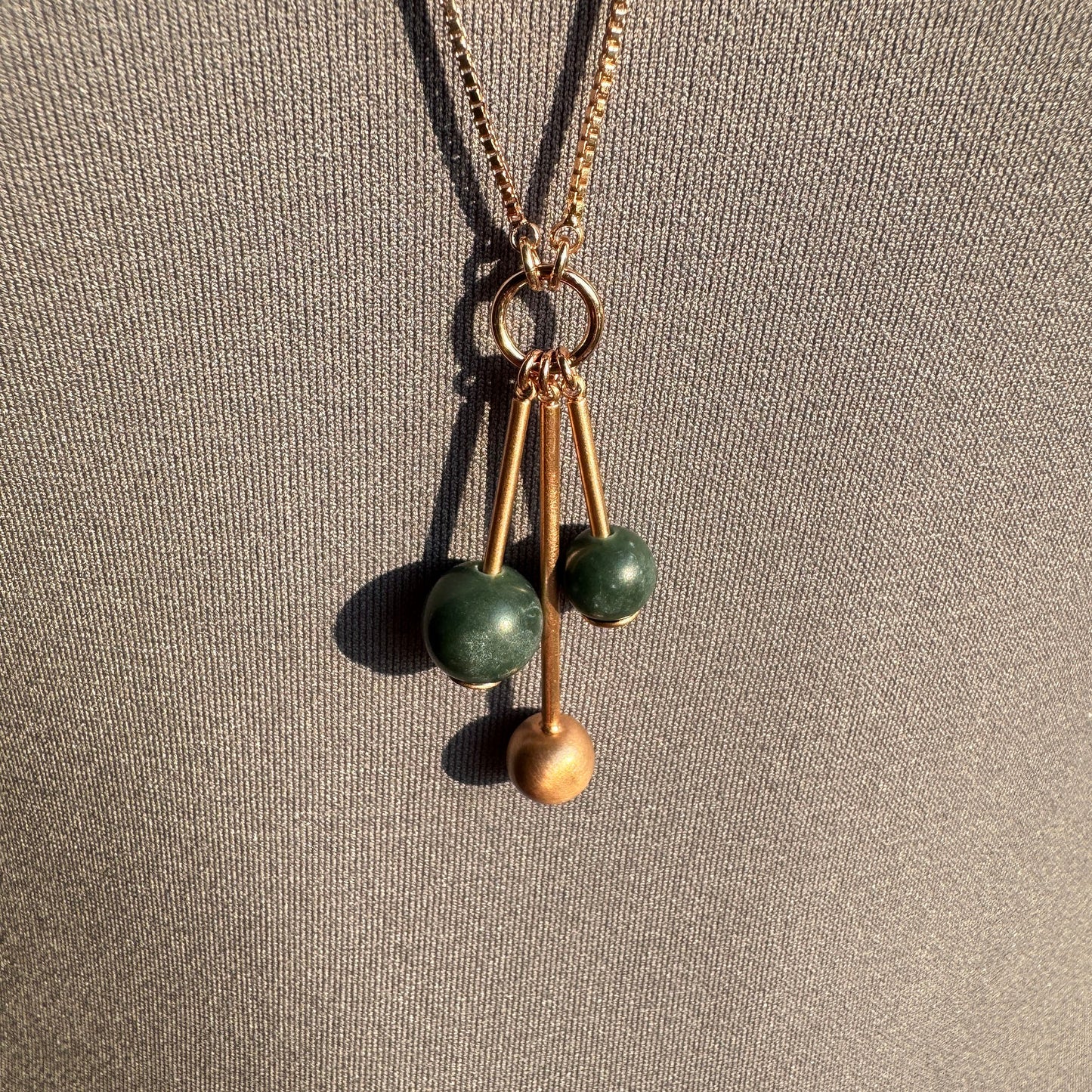 Collier doré rose avec perles vertes et design moderne