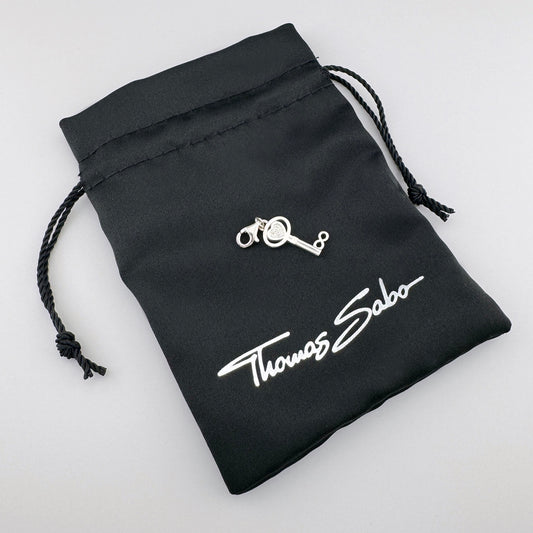 Silver Thomas Sabo key charm displayed on its branded black pouch