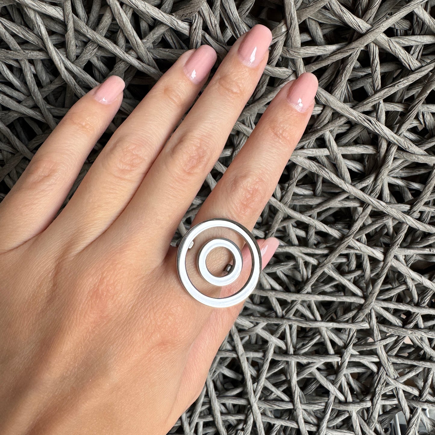 Polished silver ring with concentric circles worn on hand in minimalist look