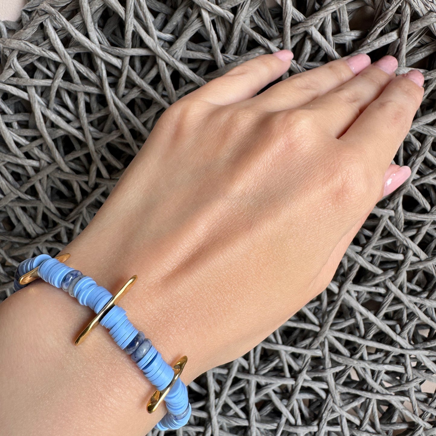 Light blue bracelet with sodalite and gold details worn on wrist