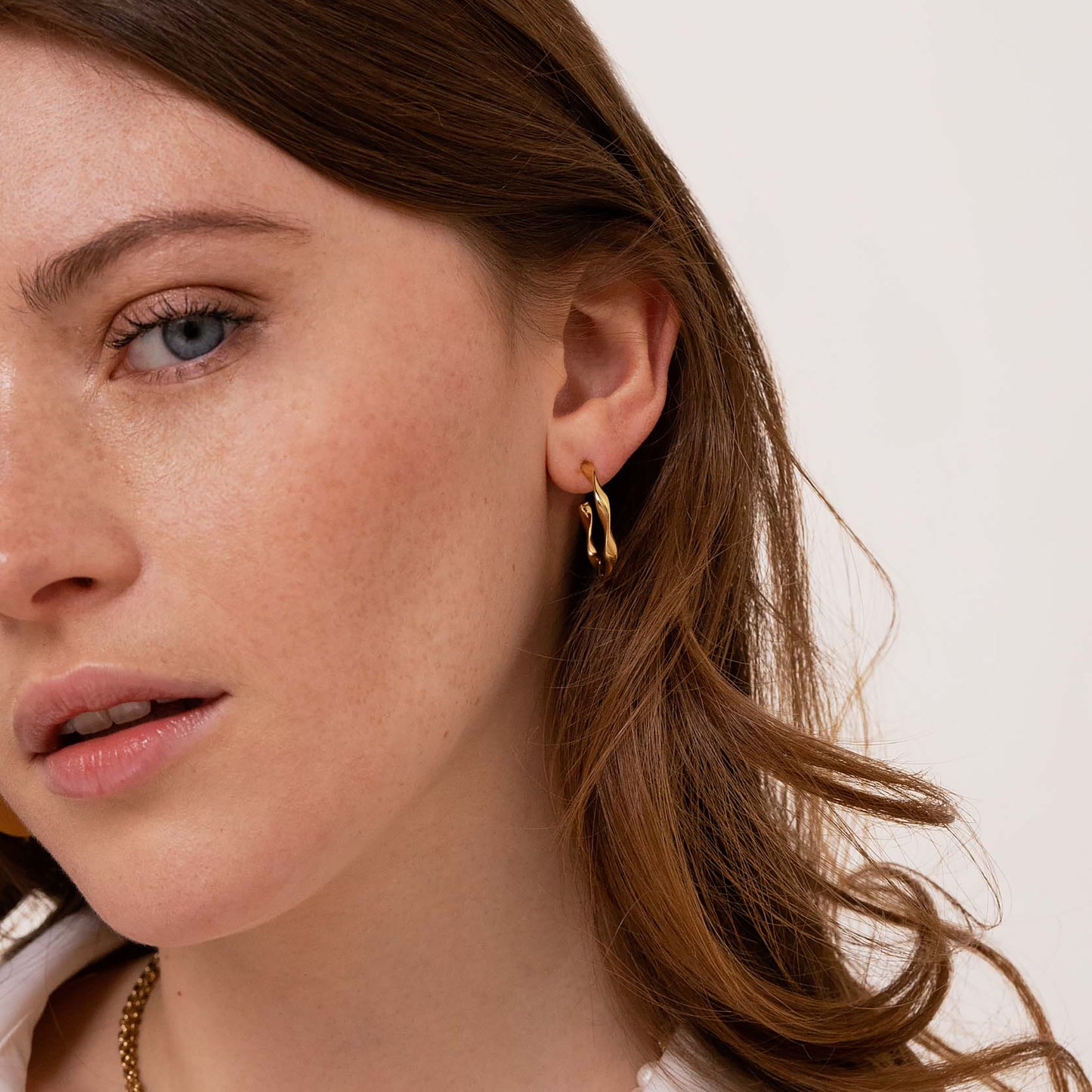 Golden twisted hoop earrings worn elegantly by a woman