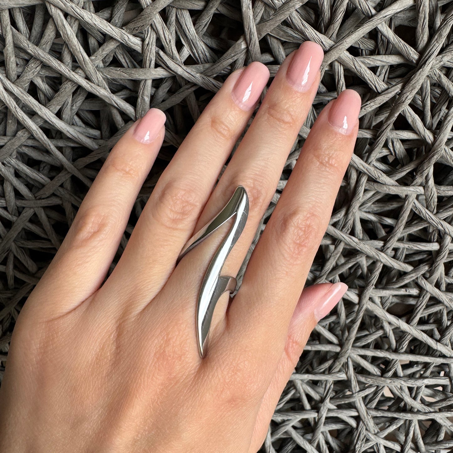 Futuristic wavy silver ring worn on hand with mirror finish and elongated form
