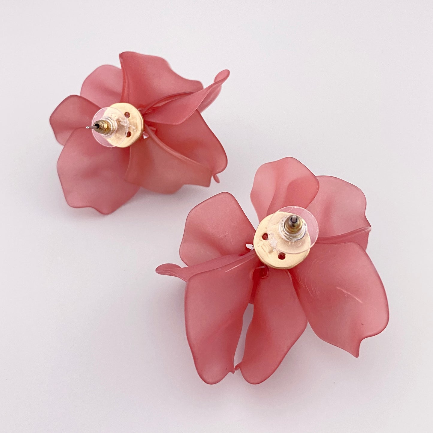 Dos des boucles d’oreilles rose poudré avec finition mate