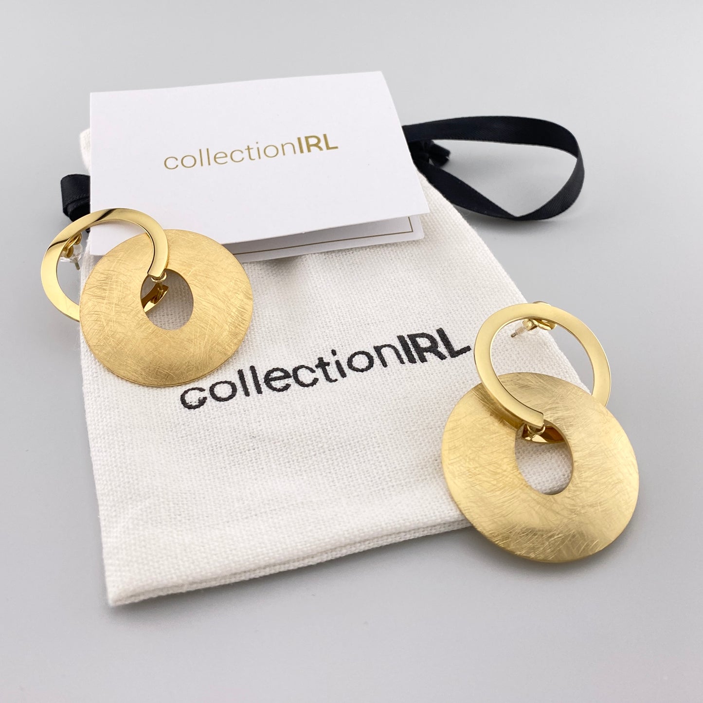 Boucles rondes IRL dorées avec pochette de marque en fond clair