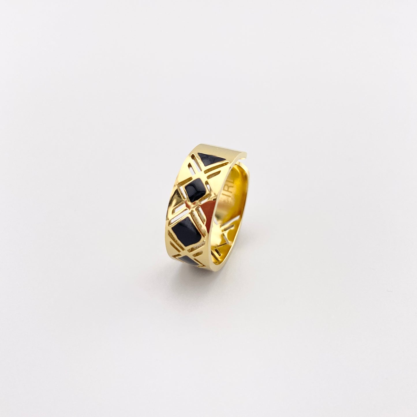 Anillo IRL con patrón geométrico y esmalte negro sobre superficie dorada