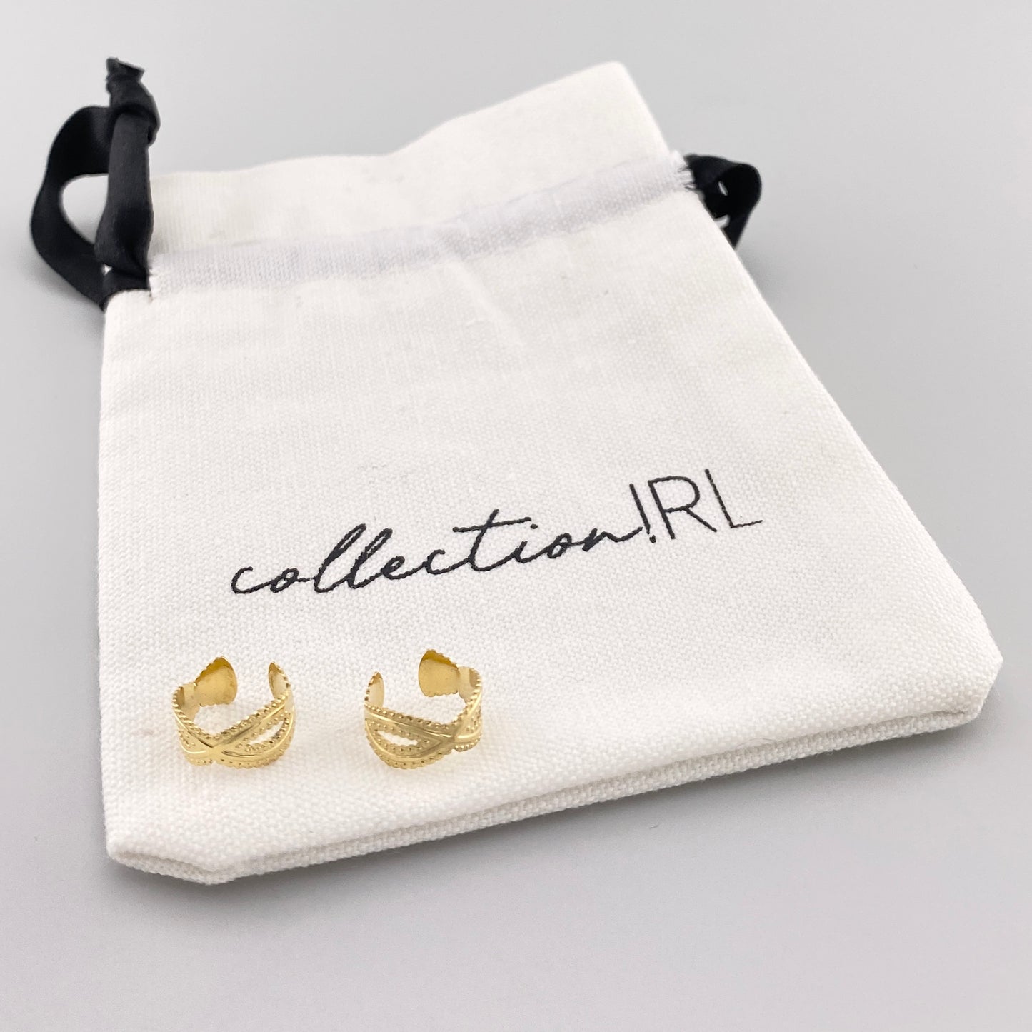 Aros tipo clip dorados con diseño tallado y bolsa de marca