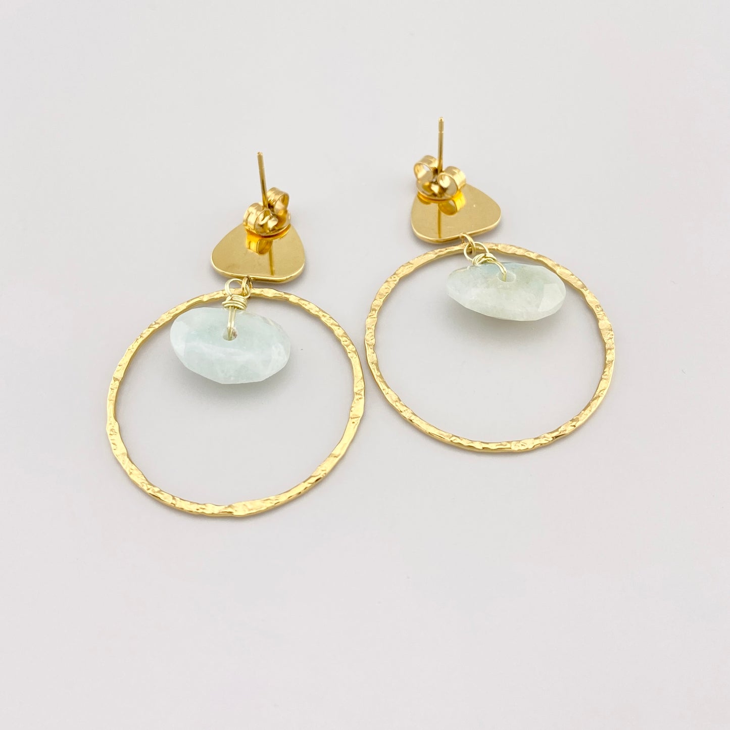 Boucles d’oreilles IRL dorées avec amazonite disposées sur fond clair