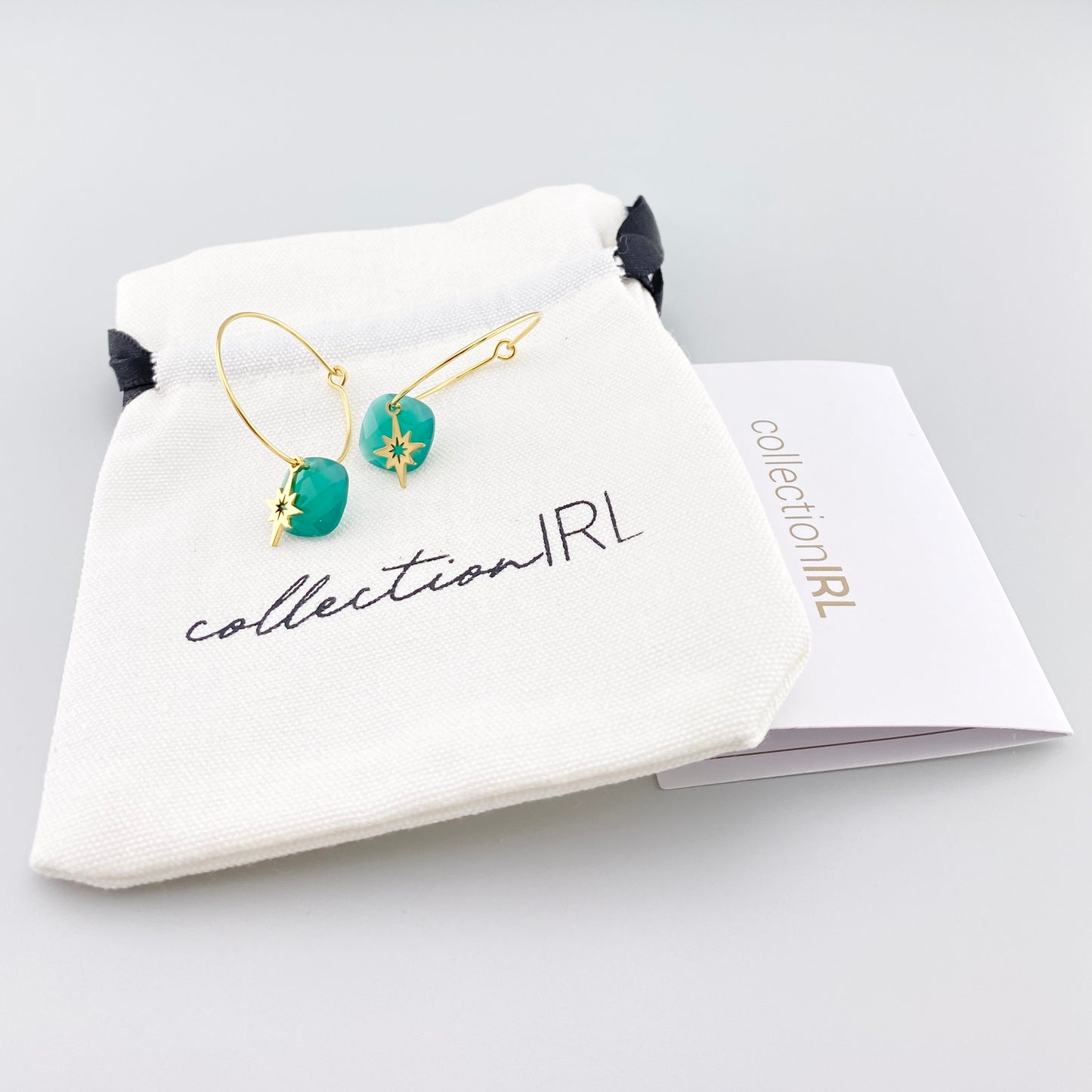 Créoles IRL dorées avec pierre verte et pendentif étoile présentées dans un écrin de marque
