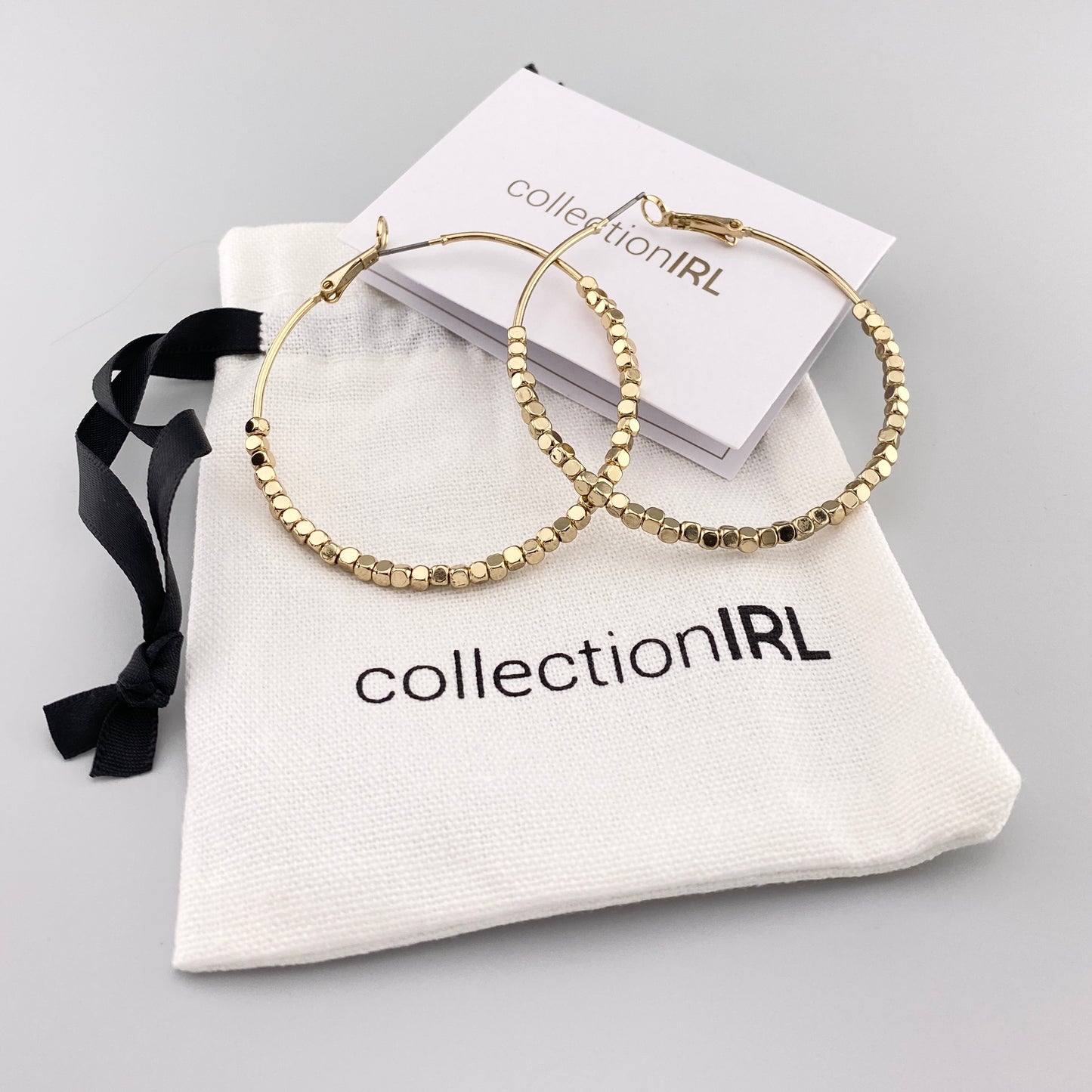 Aros dorados con detalles facetados y bolsa de marca IRL