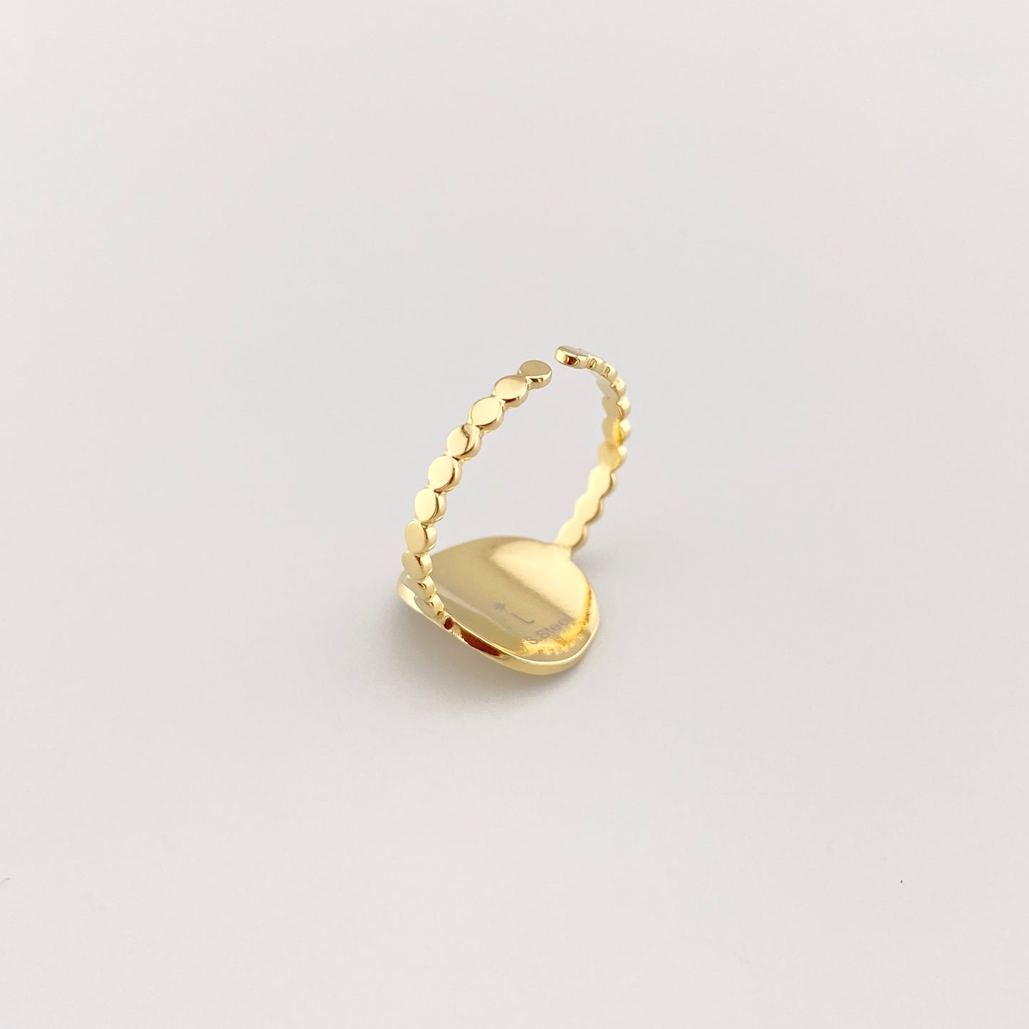 Gold IRL ring with star motif and crystal laid flat on light background