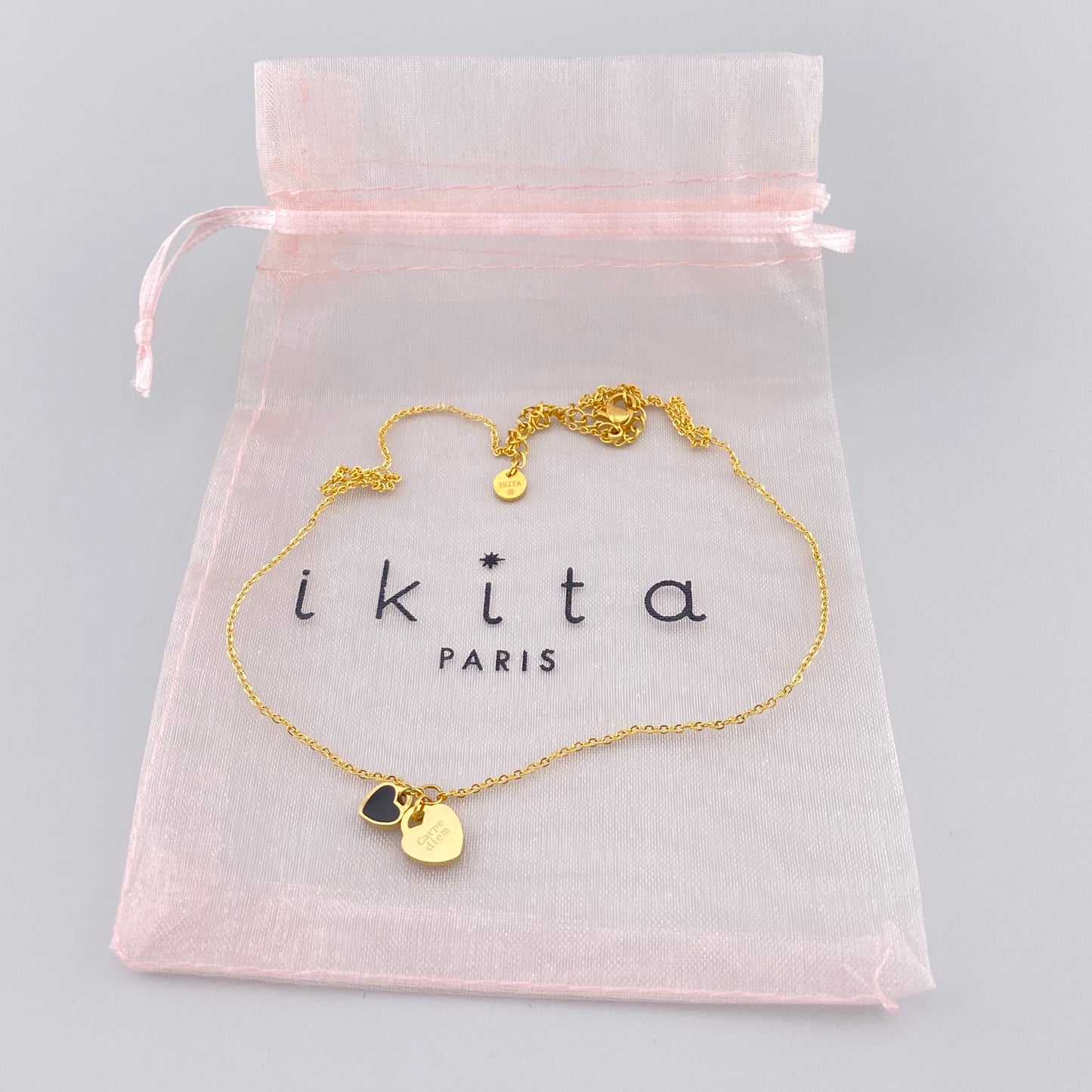 Collier Ikita doré à deux cœurs présenté dans une pochette rose