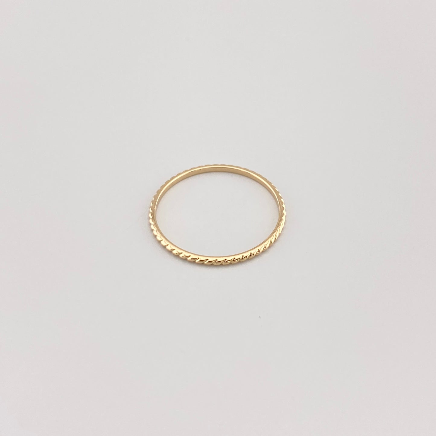 Minimalistyczny pierścionek IRL z pozłacaną powierzchnią na białym tle