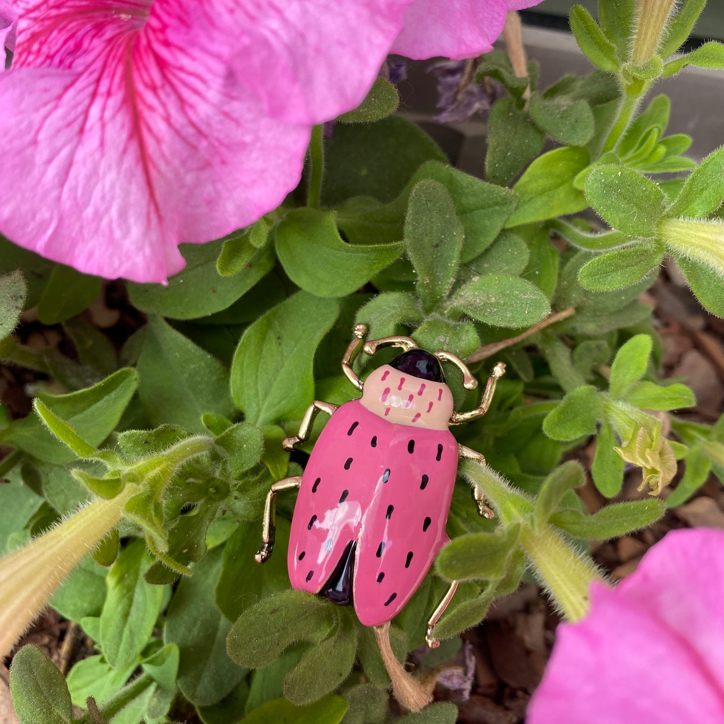Broche scarabée rose posée sur des fleurs, style fantaisie