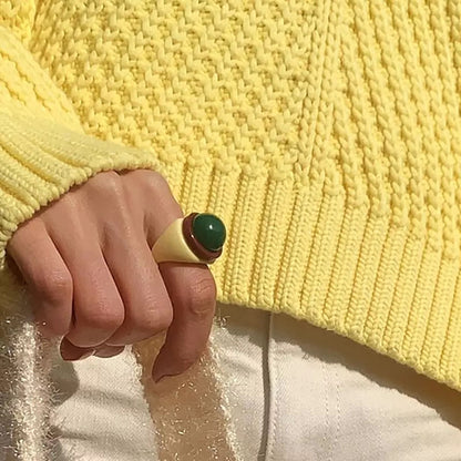 Cream plastic ring with a green sphere and burgundy accent.