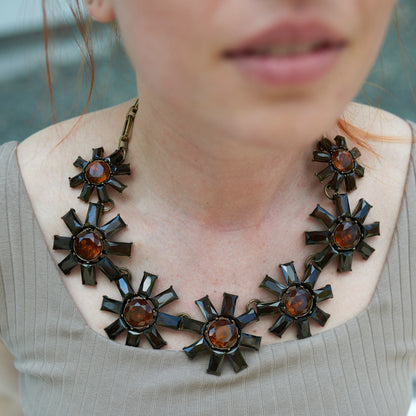 Statement necklace with antique gold metal details and brown crystals arranged in a floral design.