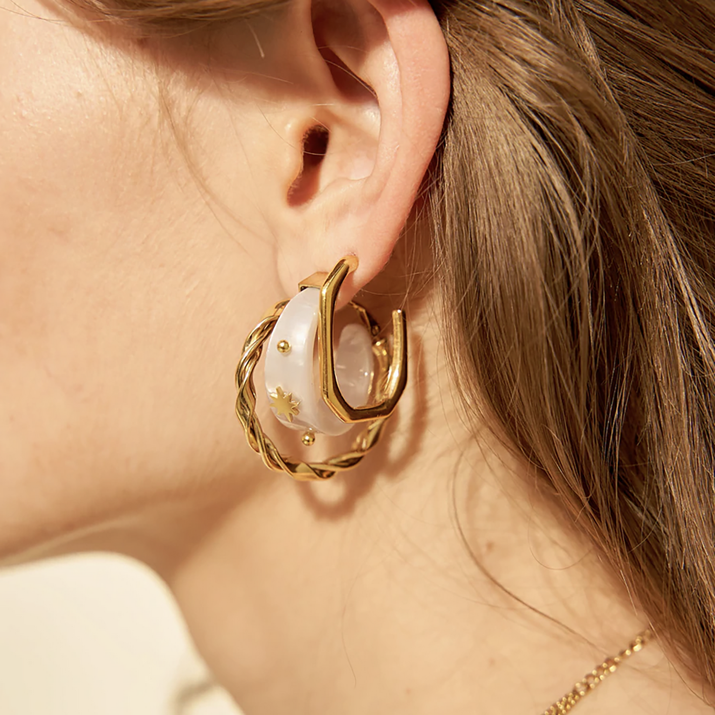 Semi-circle earrings in white material with gold accents, French brand Ikita.