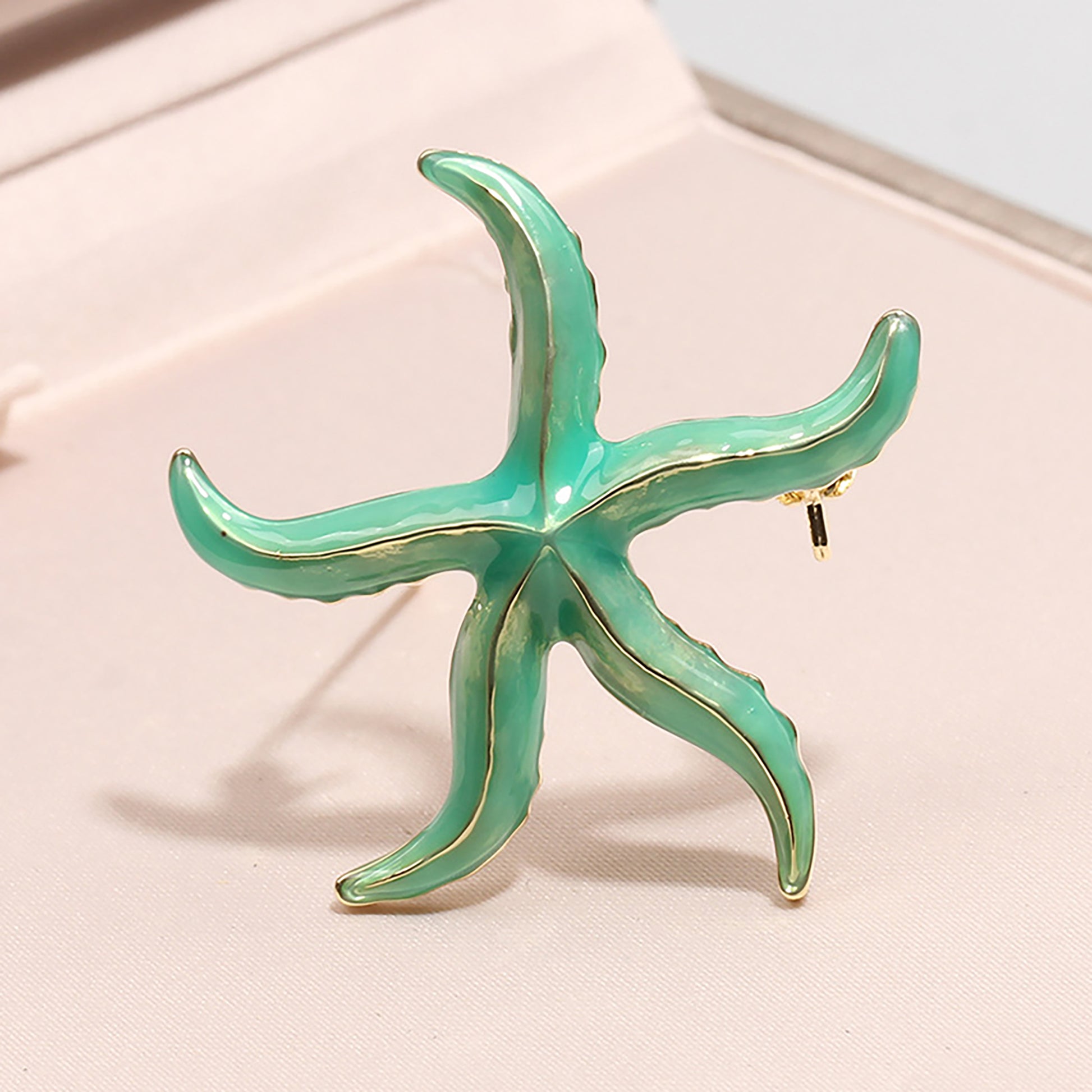 Broche verde en forma de estrella de mar con detalles dorados.