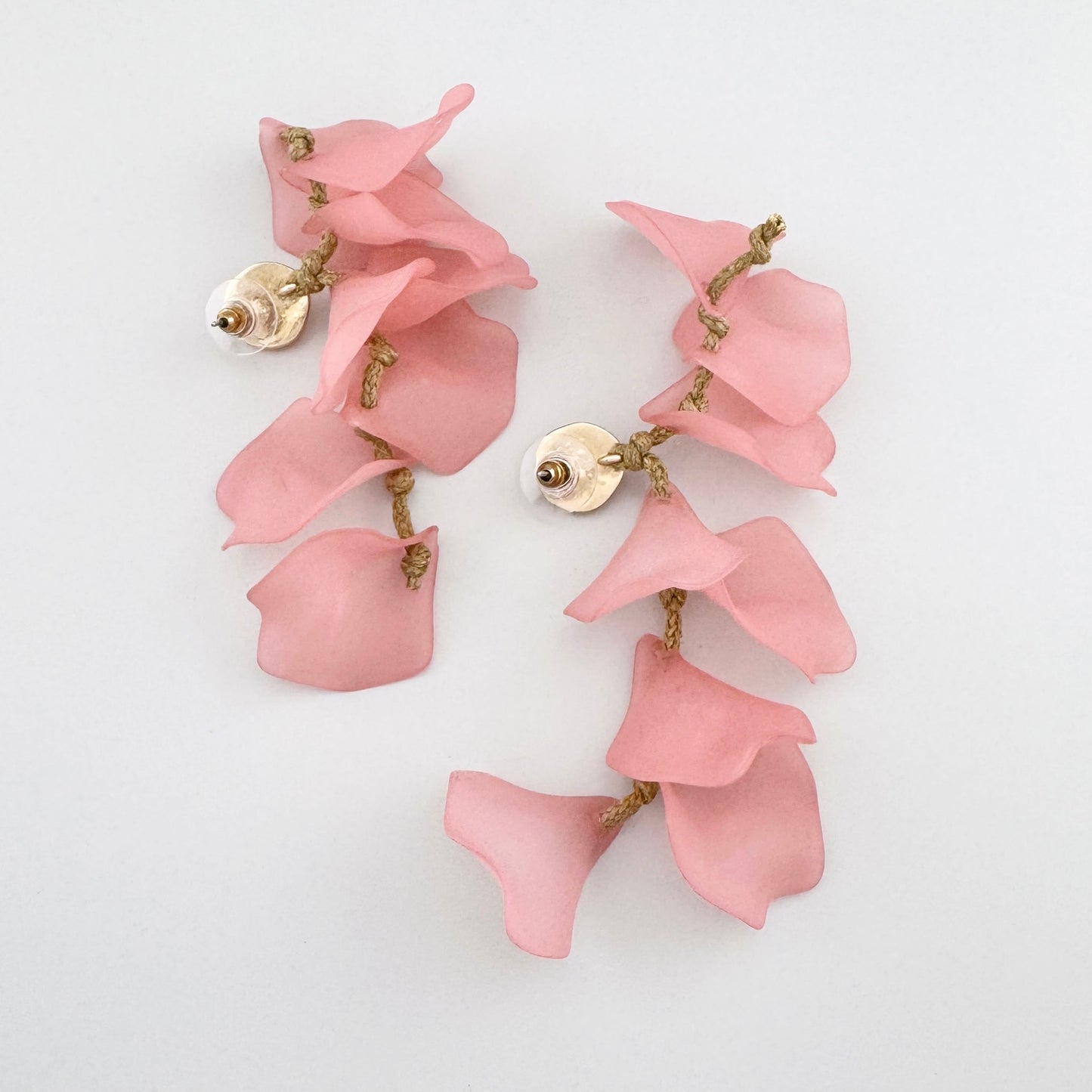 Dangling earrings with pink flower petals and gold details.