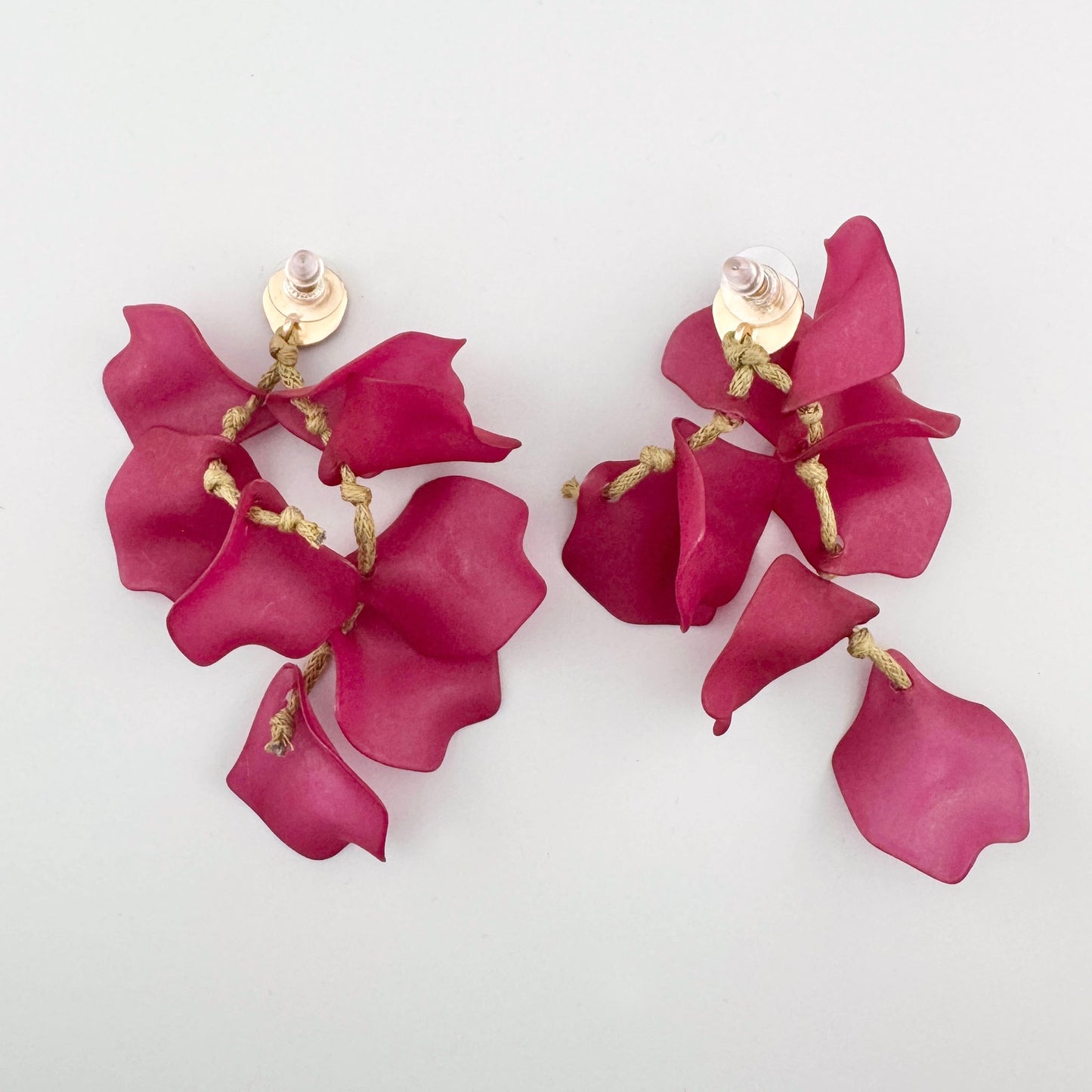 Dangling earrings with pink flower petals and textured gold clasps.