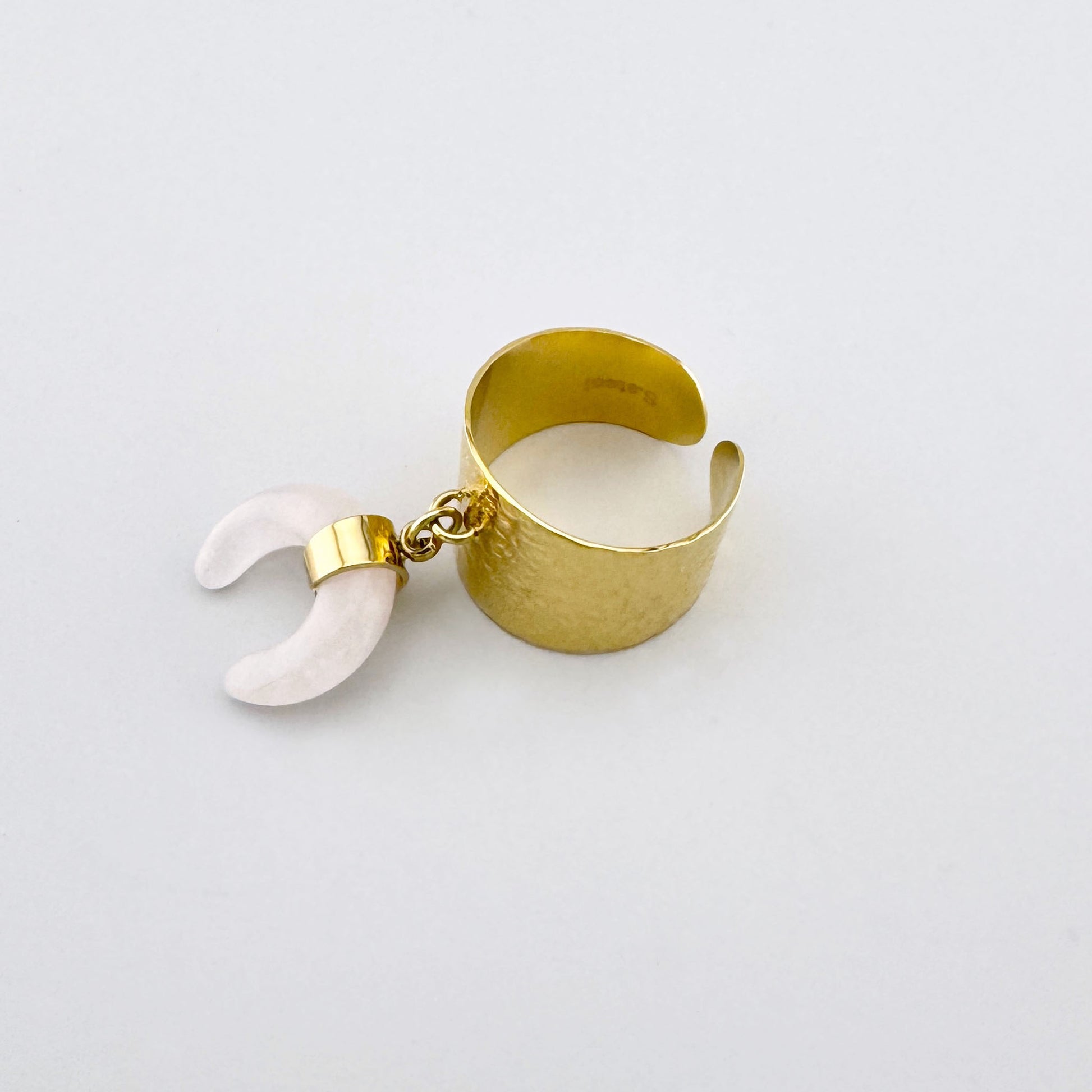 Anillo dorado con banda ancha martillada y colgante de cuarzo rosa en forma de media luna, marca francesa Ikita.