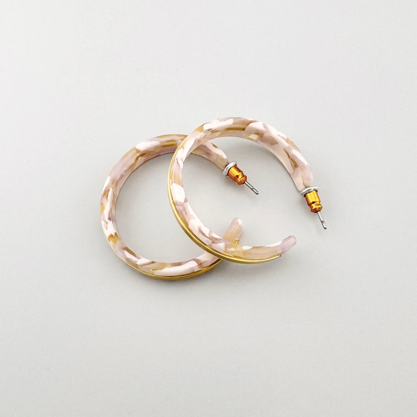 Aros de acrílico marmolado en tonos beige y dorado, marca danesa Pilgrim.