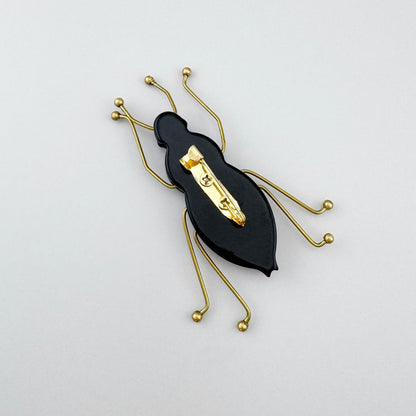 Broche con forma de escarabajo estilizado de cuerpo acrílico rosa y azul marino, marca española Sonata.