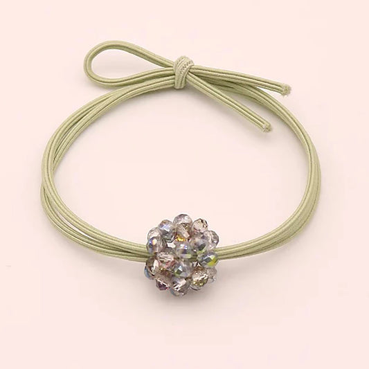 Light green hair tie with a shiny bead in the shape of a flower.