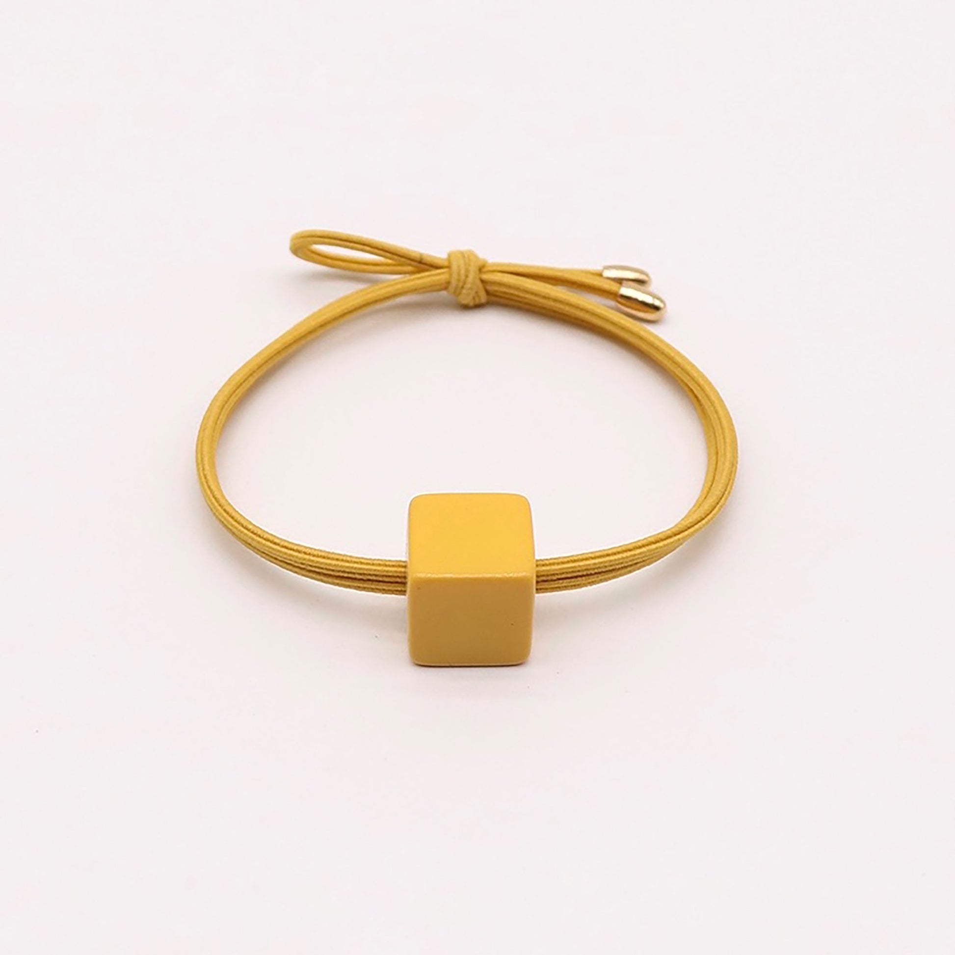 Yellow hair tie with a minimalist square-shaped ornament.