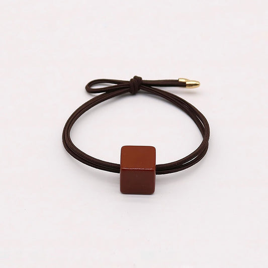 Brown hair tie with a glossy square-shaped ornament.