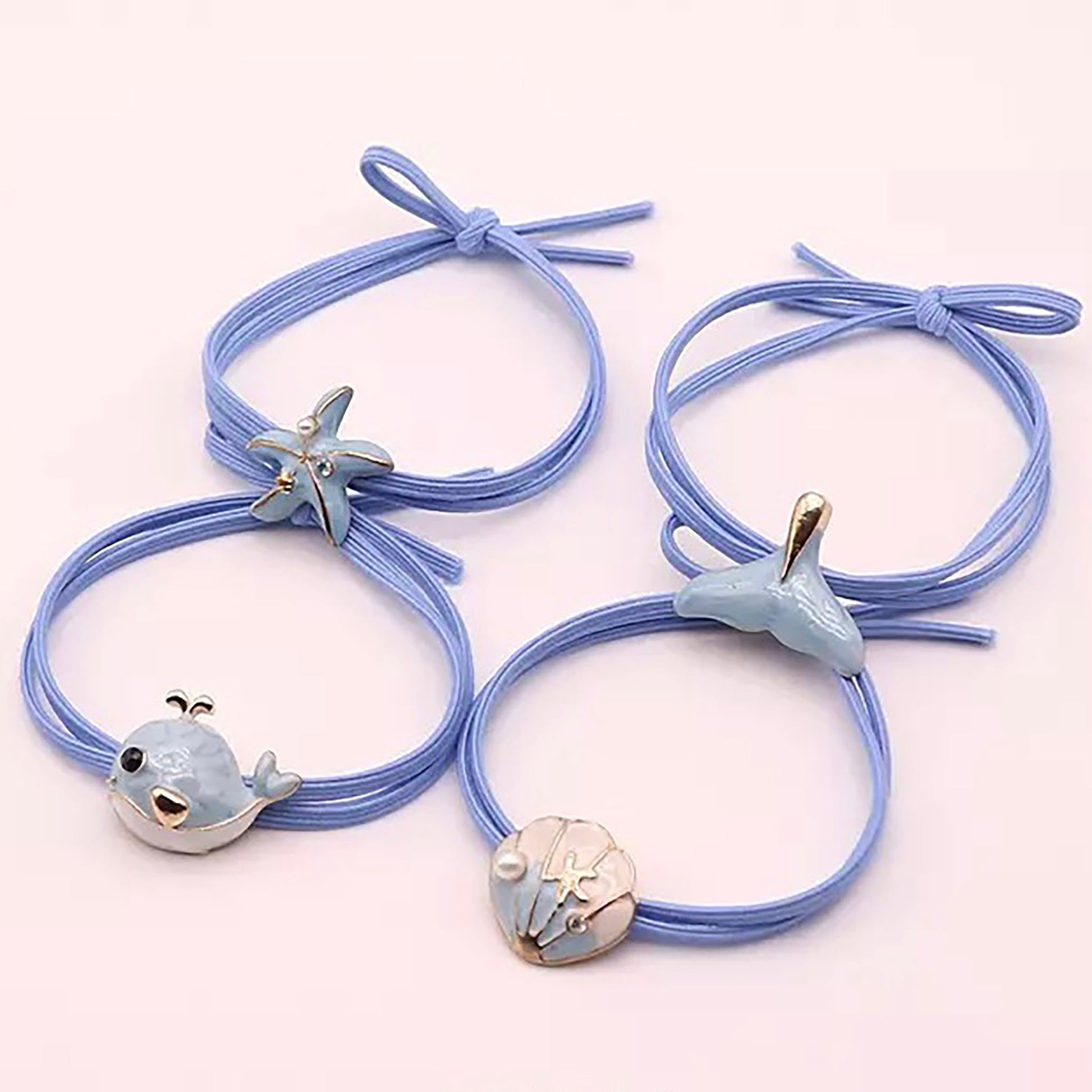 Hair tie with decorative seashell charm, gold starfish, pearl, and blue detail.