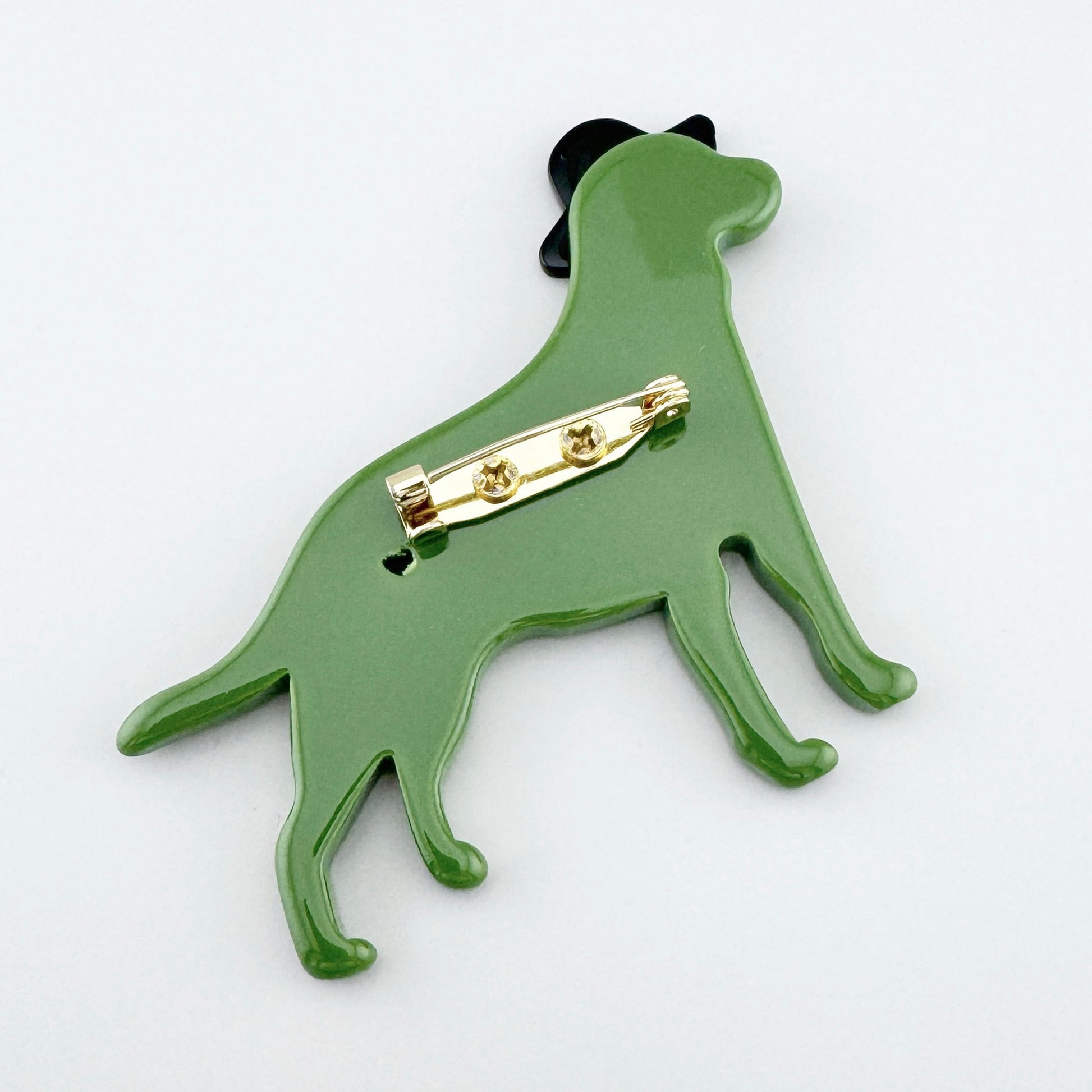 Glossy green dog-shaped brooch with a black hat accen