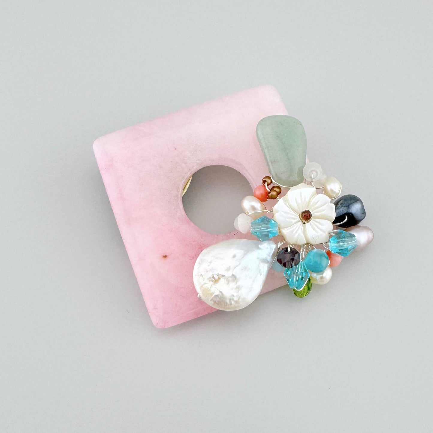 Square-shaped brooch made of natural pink stone, decorated with mother-of-pearl and colorful gemstones, Spanish brand Sonata.