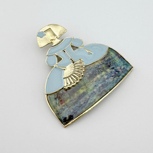 Brooch in the shape of an elegant lady in a pastel dress, made of metal and enamel.