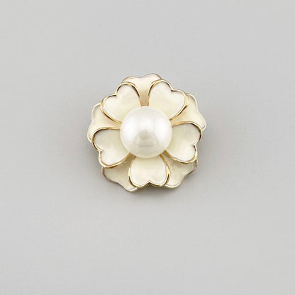 Flower-shaped brooch with a white pearl center and gold accents.