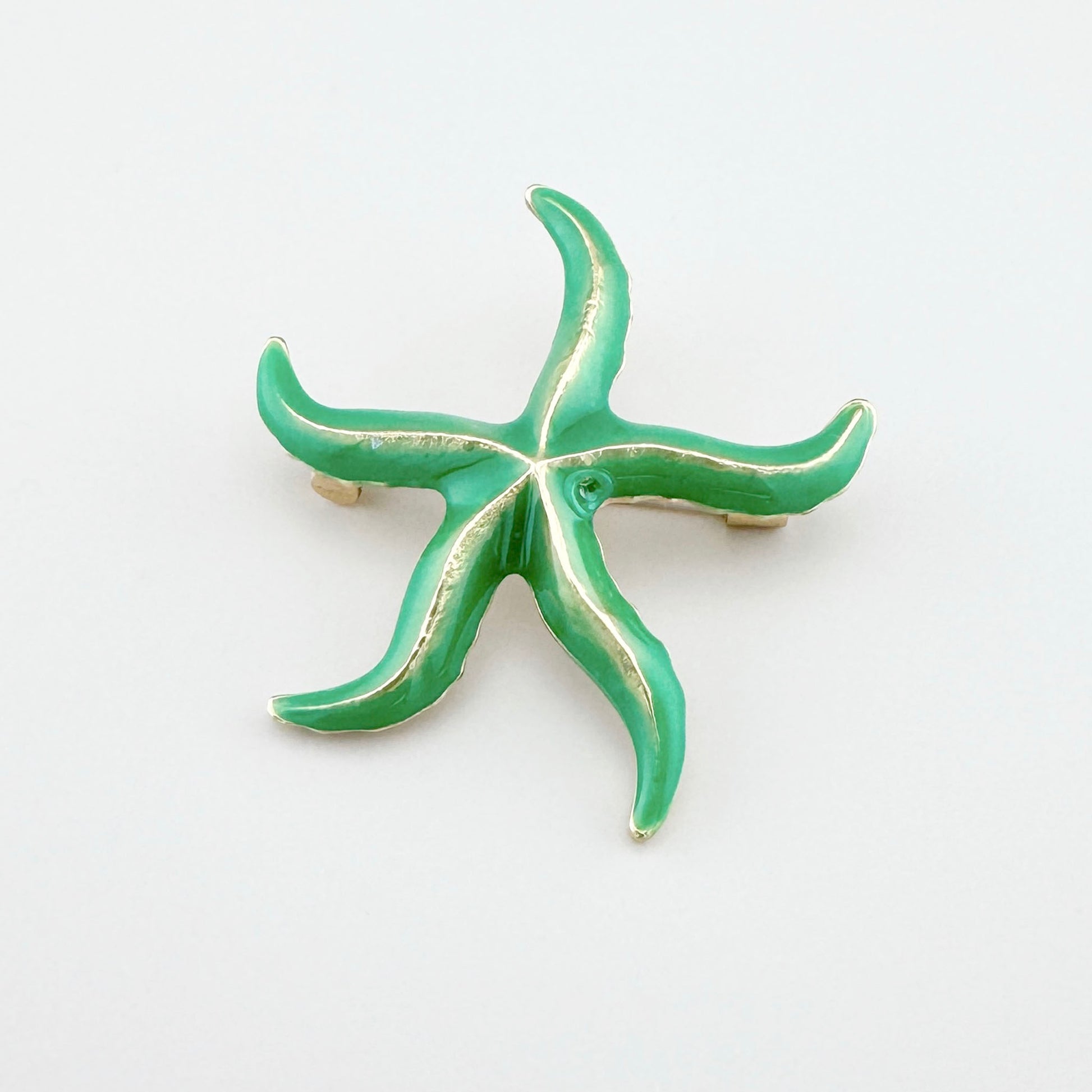 Green starfish brooch with shiny gold accents.