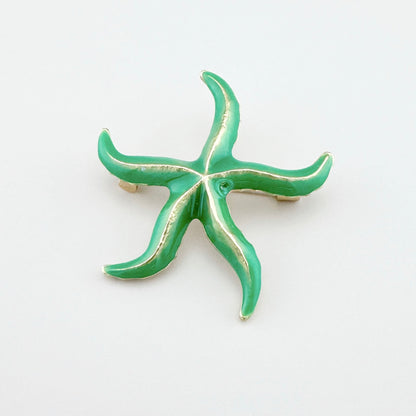 Green starfish brooch with shiny gold accents.