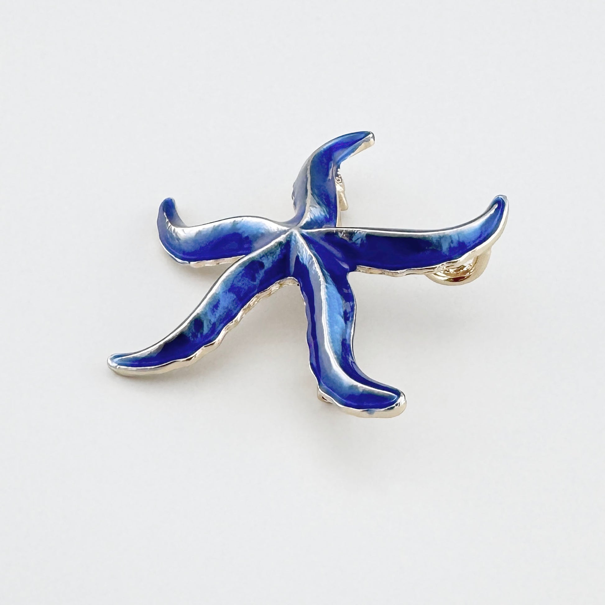 Broche azul en forma de estrella de mar con detalles dorados.