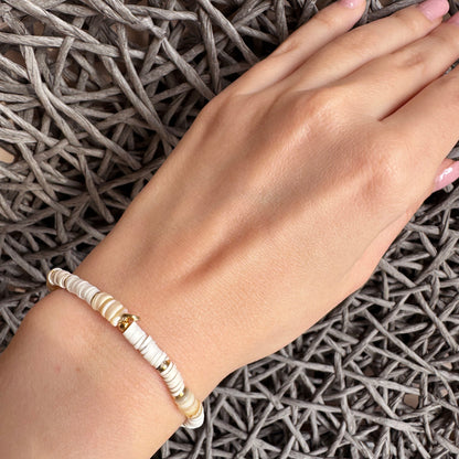 Elastic bracelet with white beads and gold-toned accents, French brand IRL.