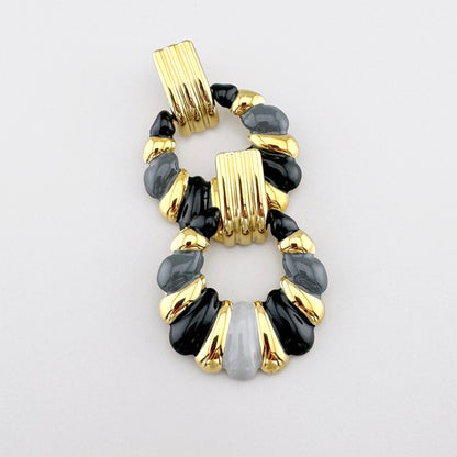 Pendientes dorados con esmalte en tonos contrastantes de negro y gris, marca francesa Ikita.