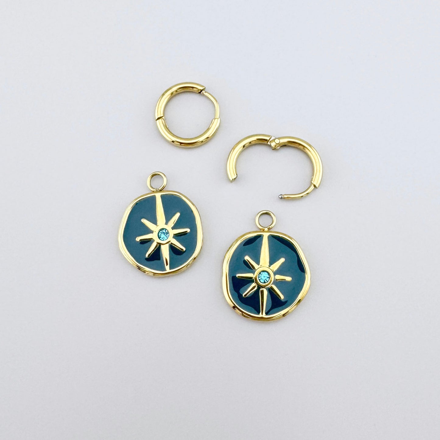 Gold earrings with turquoise enamel and star motif, adorned with a light blue crystal.