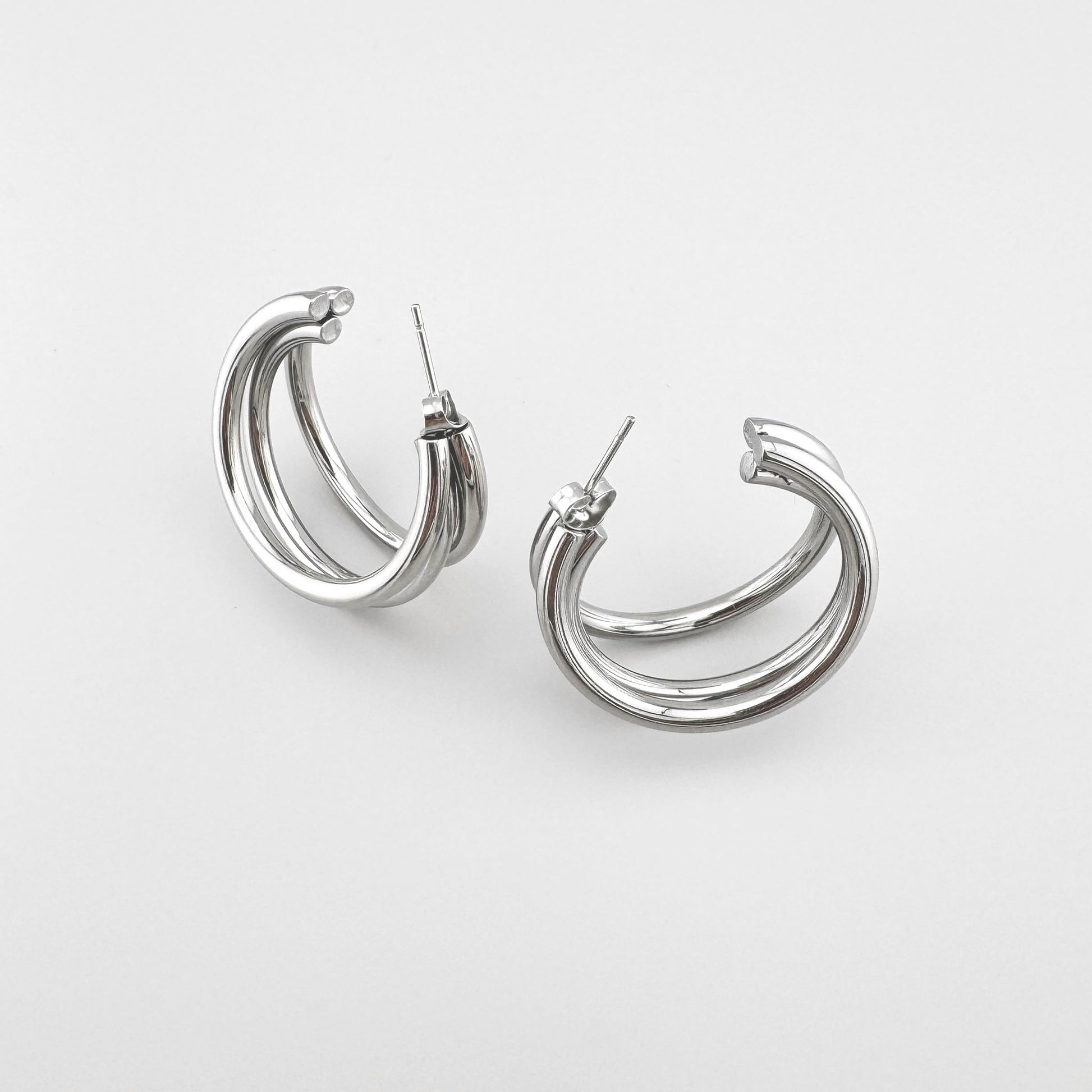 Silver-colored earrings with a triple design, creating an overlapping hoop effect, Spanish brand Maravillas.