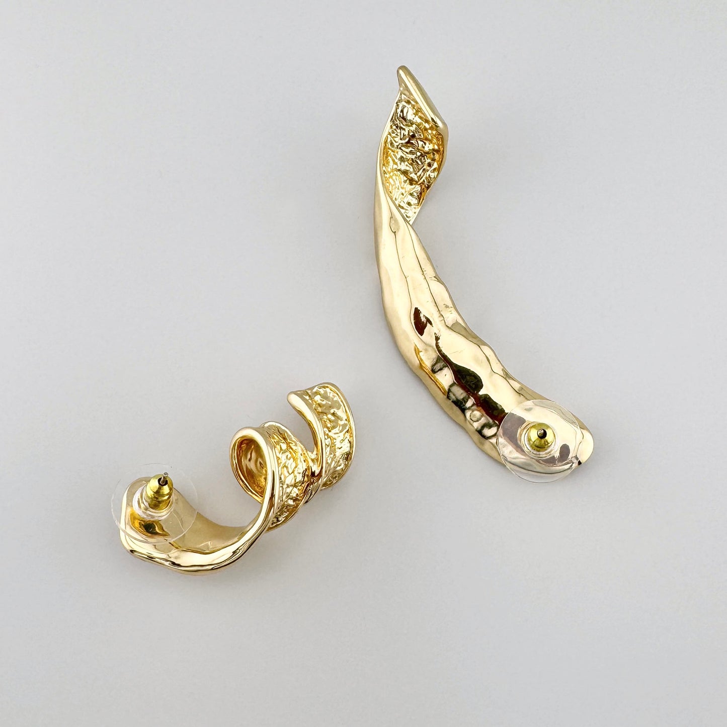 Boucles d'oreilles asymétriques dorées avec texture martelée et forme artistique. Marque Cannelle.