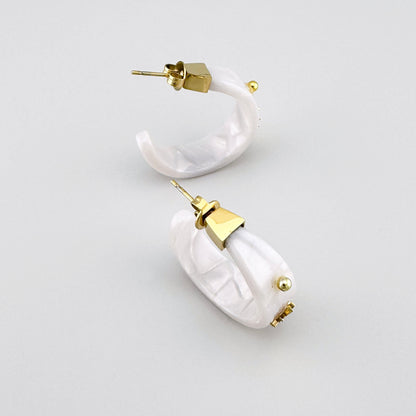 Boucles d'oreilles semi-circulaires en matière blanche avec accents dorés, marque française Ikita.