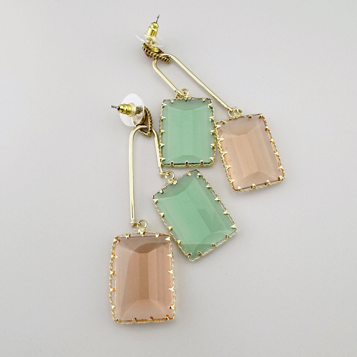 Boucles d'oreilles dorées avec des éléments en verre facetté rectangulaire dans des teintes pastel de vert et de pêche.