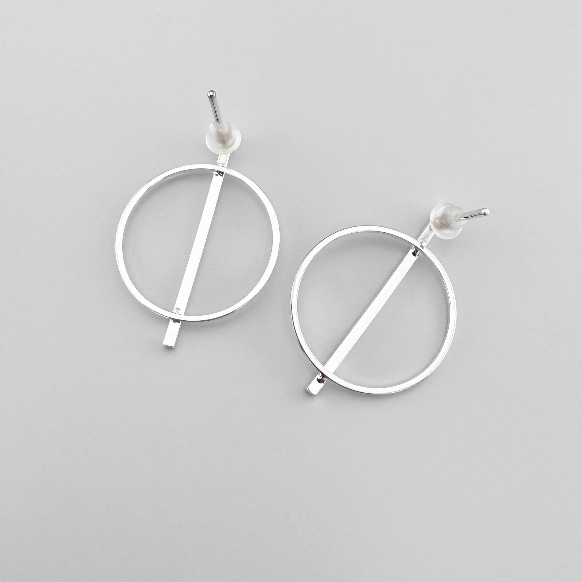 Circle earrings with silver finish and a straight line, minimalist design.