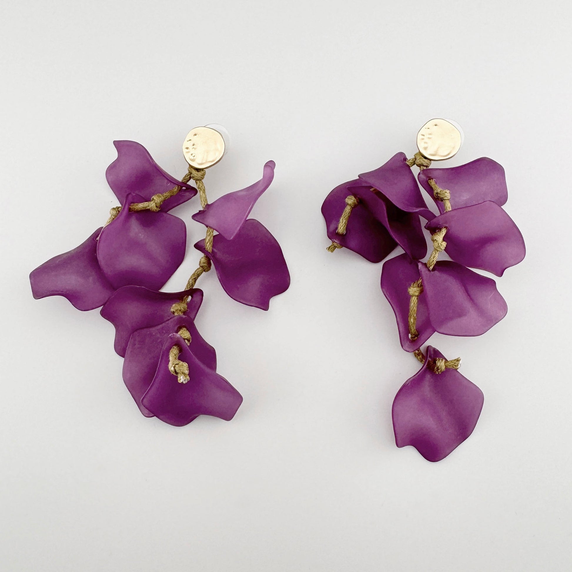 Long earrings with purple petal-shaped elements, decorated with decorative strings and gold-tone hammered texture clasps.