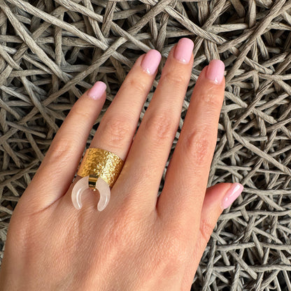 Gold-tone ring with wide hammered band and pink quartz crescent pendant, French brand Ikita.