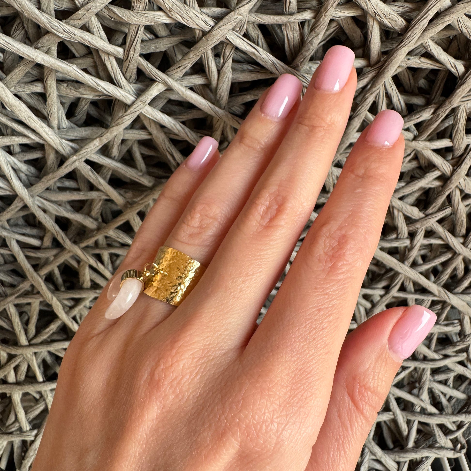 Goldfarbener Ring mit breitem, gehämmertem Band und Anhänger aus Rosenquarz in Halbmondform, französische Marke Ikita.