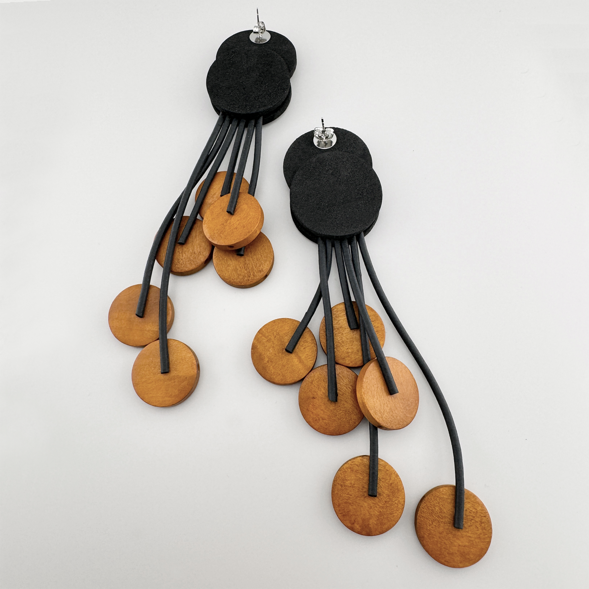 Earrings with black circles and wooden accents on dangling strings.