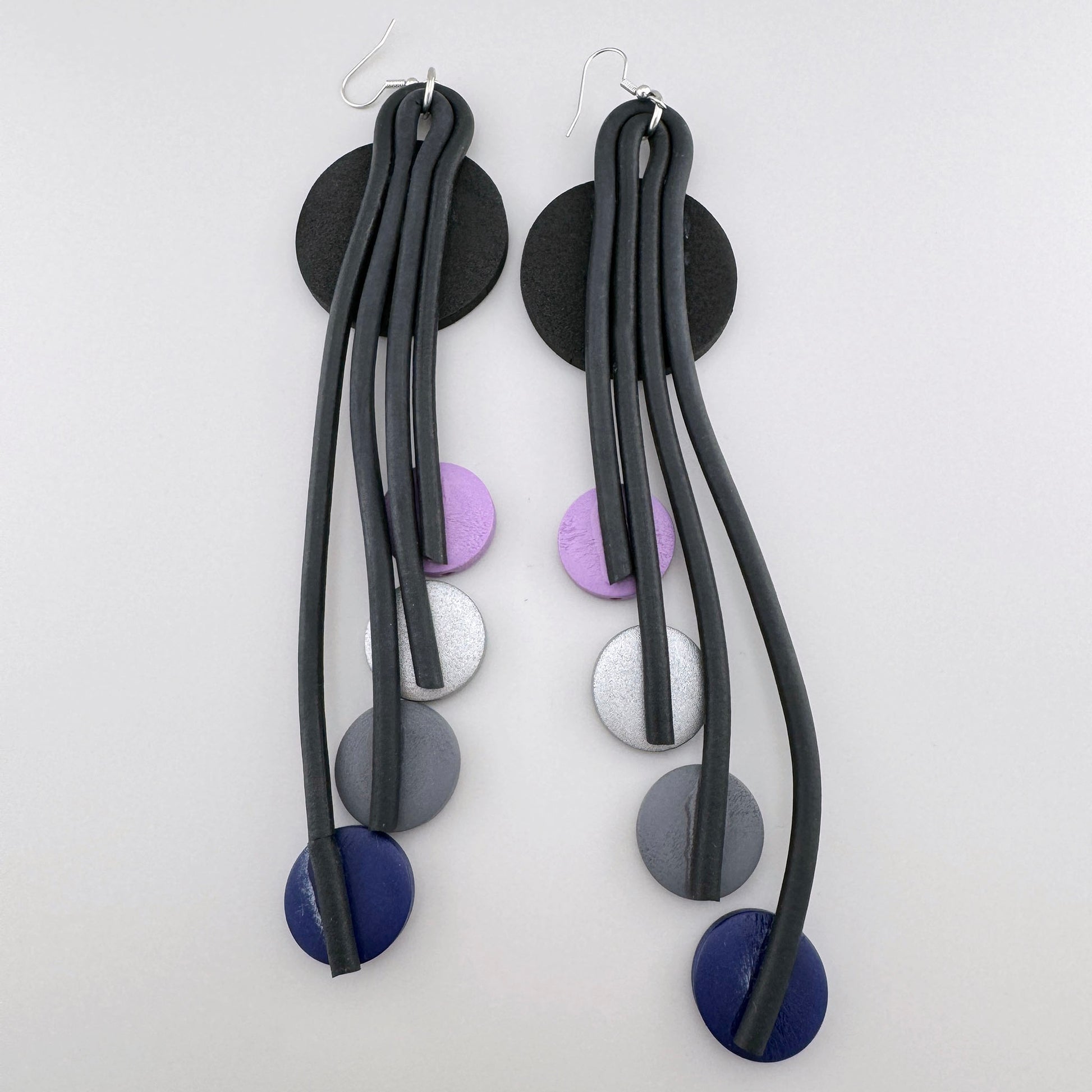 Earrings with black circles and colorful accents in purple and silver tones.